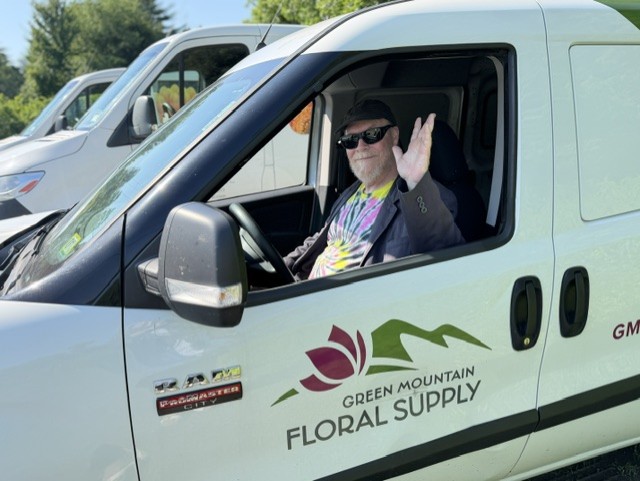 Driver "Blue" sitting in driver's seat of Green Mountain Floral Supply van.