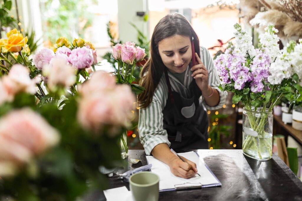Florist in shop on phone taking an order