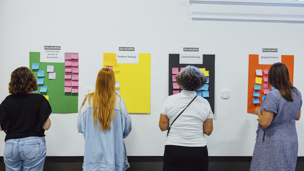 Petals and Best Practices event attendees looking at topic boards