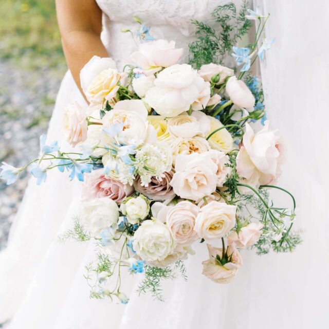 bride holding bouquet of white, light pink and blue flowers