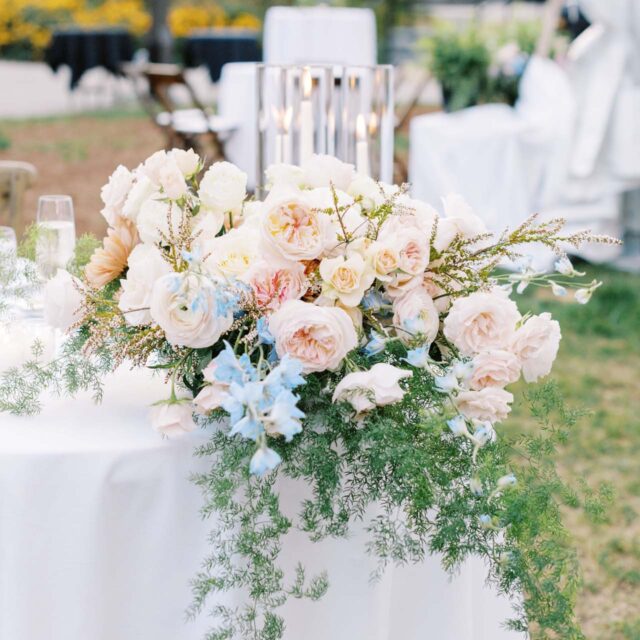 floral arrangement of light pink and blue flowers on a white tablecloth
