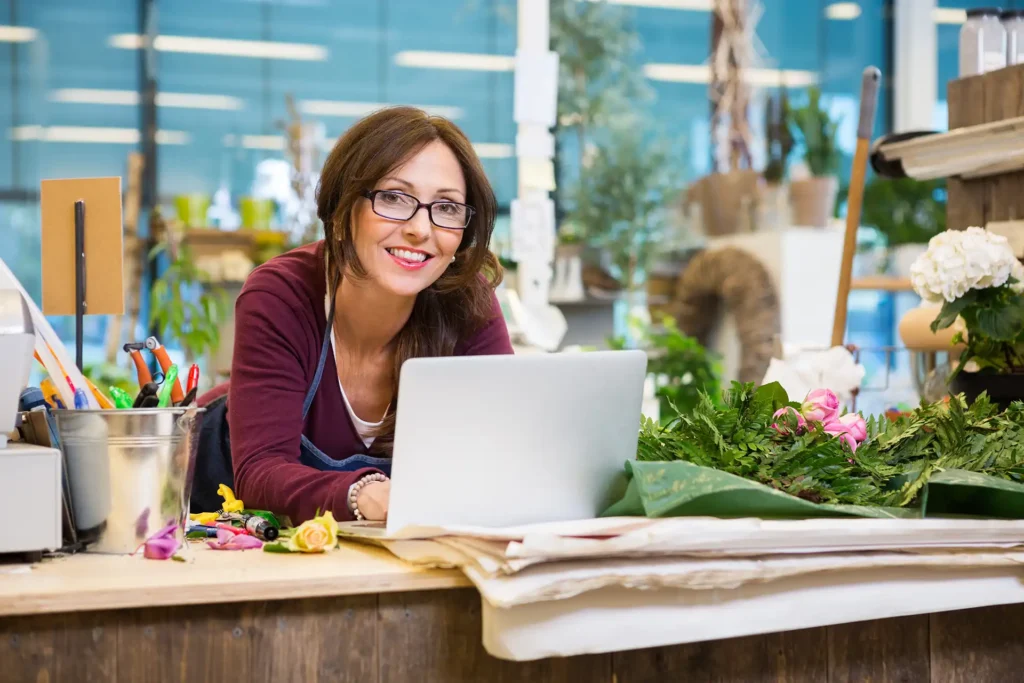 woman at a laptop with flowers on counter next to her